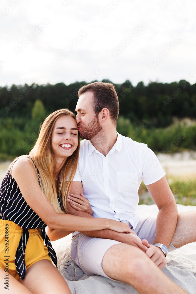 man and a woman are kissing and hugging on a sandy beach man and a woman are kissing and hugging on a sandy beach