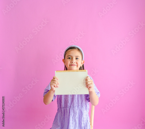 Pretty little girl holding a blank notebook. 