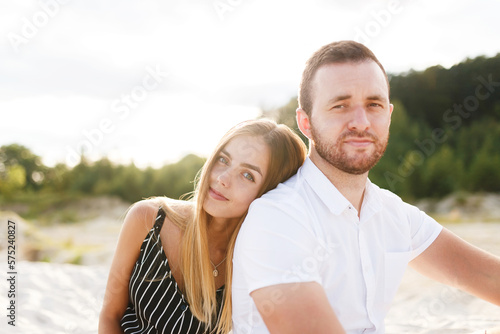 couple in love laughing sitting on sandy beach on vacation