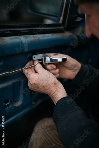 The old technician installing the car door at home closeup