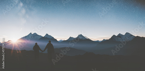 Silhouette of two person on top of mountain peak. / Holding Hands / coaching goal, success and teamwork concepts - Mountains Mountaineer / Space for Text / Blank Space / Copy Text