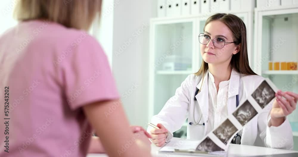 Doctor shows an ultrasound image to pregnant woman in clinic Doctor shows an ultrasound image to pregnant woman in clinic