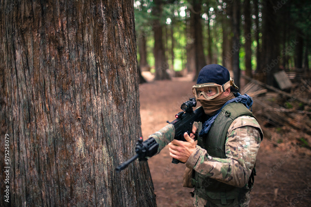 A man carries an automatic weapon while walking through the forest. A man carries an automatic weapon while walking through the forest.