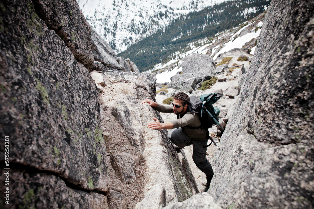 A backpacker scrambles up a rock chimney. A backpacker scrambles up a rock chimney.