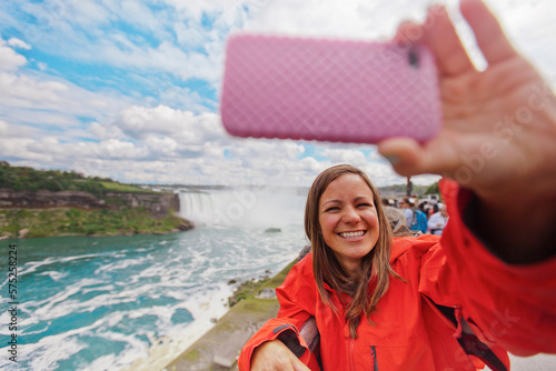 A female tourist takes a selfie with  Niagara Falls in the background.