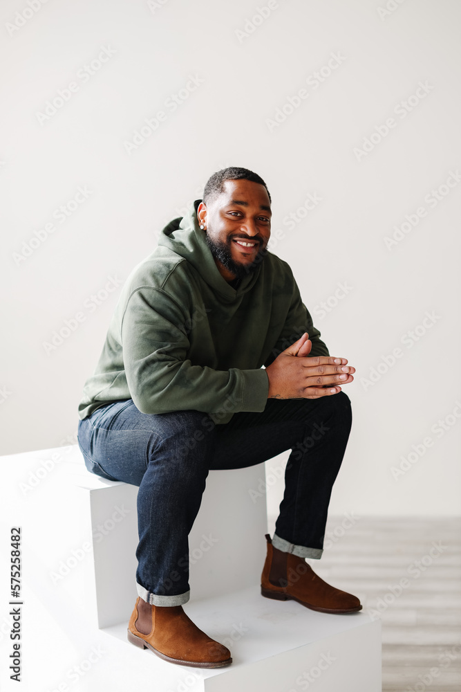 Joyful smiling mature Black man sitting down inside Joyful smiling mature Black man sitting down inside