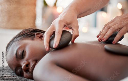 Black woman, hot stone massage, spa and hands of masseuse, holistic and wellness, therapy and treatment. Health, peace of mind and rocks with zen, stress relief for people and back skin detox