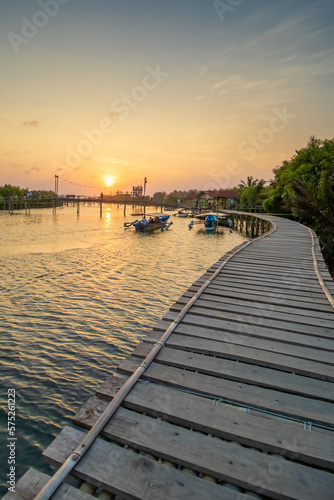 A wooden bridge built at the mouth of a river where there is a mangrove forest while sunset.
