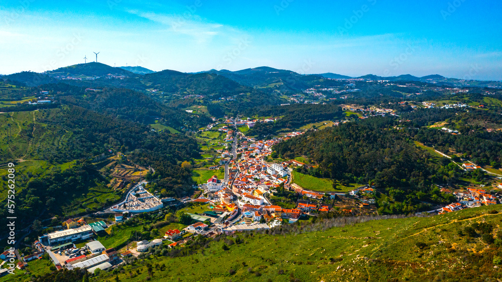 Drone view of a beautiful small European city with a beautiful hilly landscape on a summer day. Top view of a European village located in a valley with a beautiful green landscape.