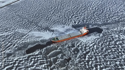 A big red ship frozen in the endless sea of ice. Aerial View of dead frozen harbour Extreme cold weather. Nature landscape famous for being heavily affected by global warming and Climate Change photo