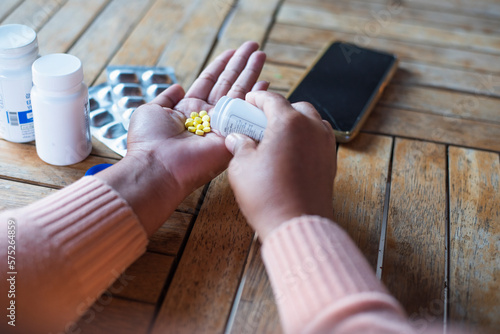 Young Asian woman holding pills in hand preparing for use The concept of taking care of one's health and helping people in the house. photo