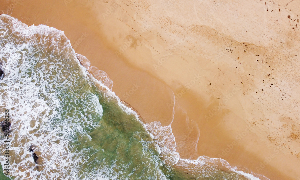 Aerial view of the ocean coast and sandy sea beach. Beautiful water background texture for tourism and advertising. Tropical coast