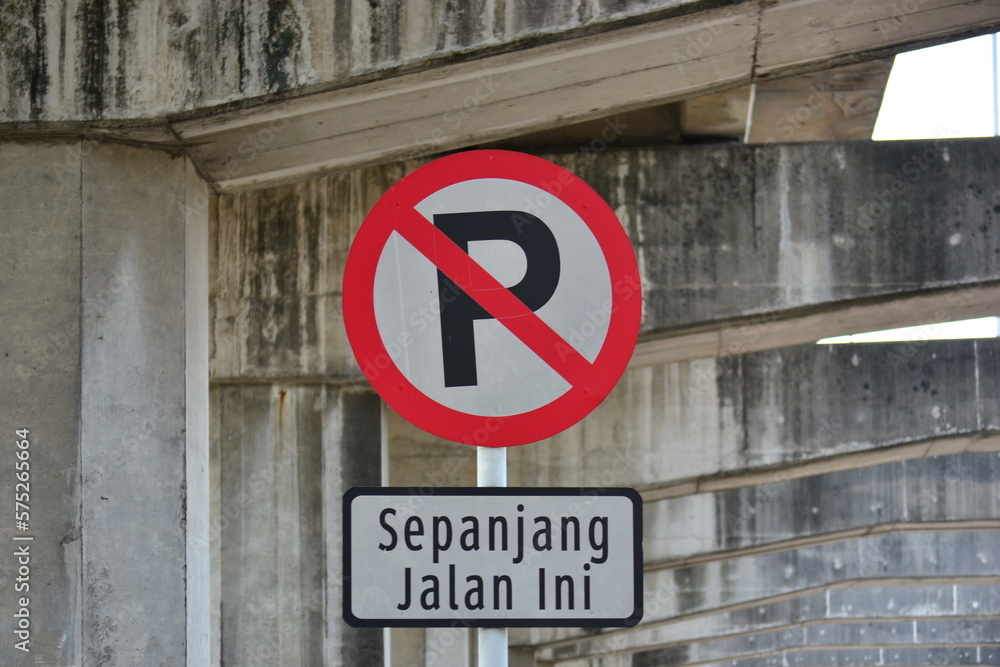 parking prohibition signs located on the side of the road under the foundation of the toll road