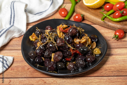 Mixed olives. Dried tomatoes, thyme, rosemary, walnuts and olives on the plate. Mediterranean flavors