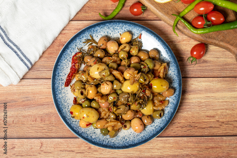 Mixed green olives. Green olive salad on wood background. Mediterranean flavors. Top view Mixed green olives. Green olive salad on wood background. Mediterranean flavors. Top view