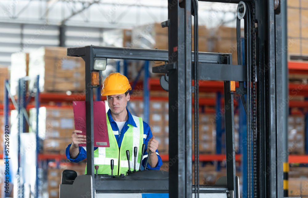 Worker in auto parts warehouse use a forklift to work to bring the box of auto parts into the storage shelf of the warehouse waiting for delivery to the car assembly line Worker in auto parts warehouse use a forklift to work to bring the box of auto parts into the storage shelf of the warehouse waiting for delivery to the car assembly line