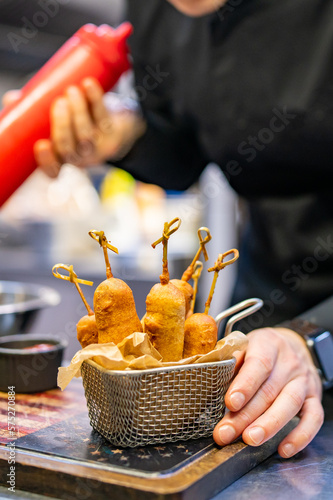 chef cookind corn dog on restaurant kitchen photo