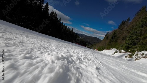Skiing. Action camera low angle view of skis of skier going downhill on alpine ski on snow slopes in the mountains. Man going downhill on ski having fun on slopes. Winter sport outdoor activity video