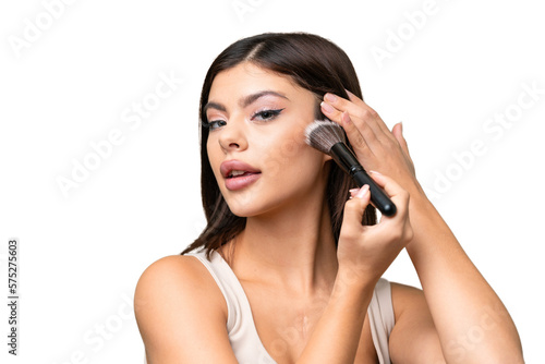 Young Russian woman with rainproof coat and umbrella over isolated chroma key background holding makeup brush