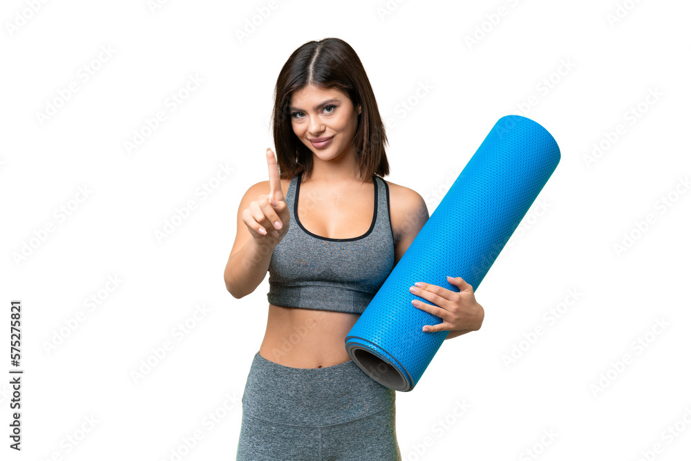 Young sport woman going to yoga classes while holding a mat over isolated chroma key background showing and lifting a finger Young sport woman going to yoga classes while holding a mat over isolated chroma key background showing and lifting a finger