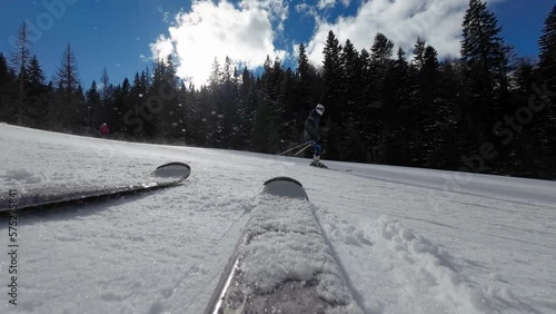 Skiing. Action camera low angle view of skis of skier going downhill on alpine ski on snow slopes in the mountains. Man going downhill on ski having fun on slopes. Winter sport outdoor activity video