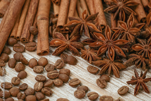 Background with cinnamon sticks, anise stars, coffee beans and nuts. Spicy trendy background. Close-up of various spices on wooden table top view