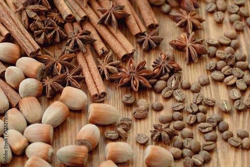 Background with cinnamon sticks, anise stars, coffee beans and nuts. Spicy trendy background. Close-up of various spices on wooden table top view