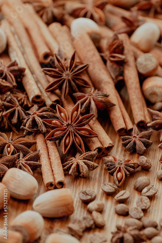 Background with cinnamon sticks, anise stars, coffee beans and nuts. Spicy trendy background. Close-up of various spices on wooden table top view