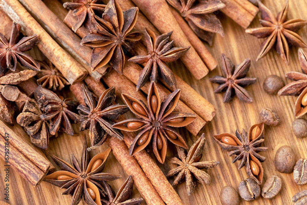 Background with cinnamon sticks, anise stars, coffee beans and nuts. Spicy trendy background. Close-up of various spices on wooden table top view Background with cinnamon sticks, anise stars, coffee beans and nuts. Spicy trendy background. Close-up of various spices on wooden table top view