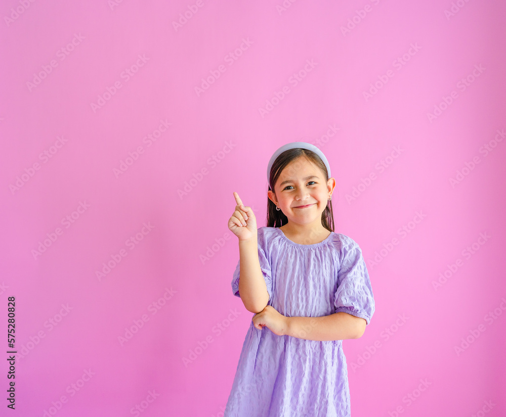 Pretty little girl standing and pointing up with one hand and other arm crossed. Pretty little girl standing and pointing up with one hand and other arm crossed.