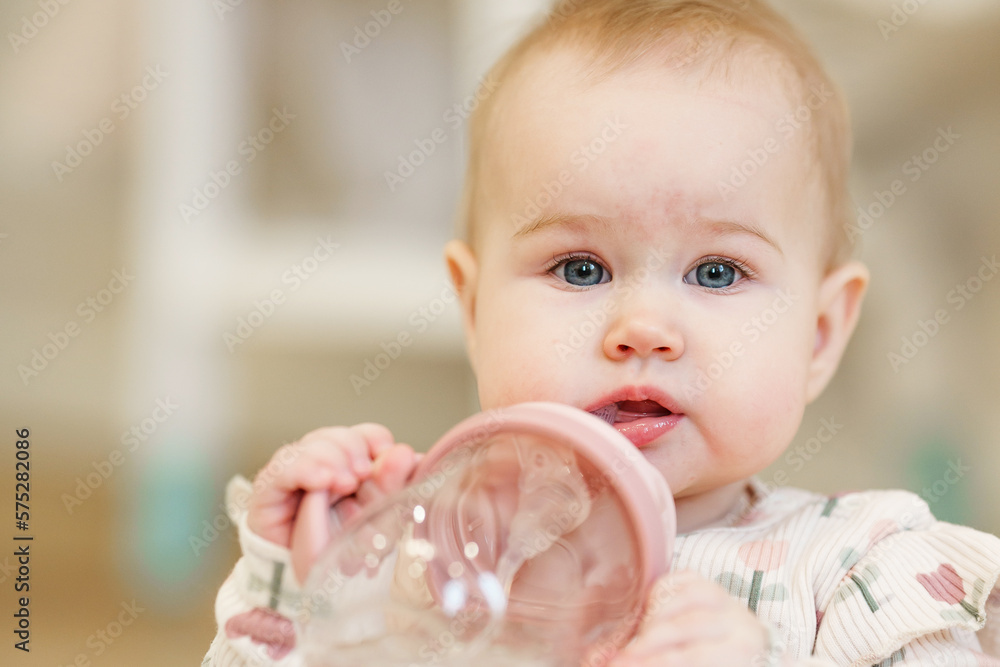 Baby toddler drinks from a baby drinking cup with a straw Baby toddler drinks from a baby drinking cup with a straw