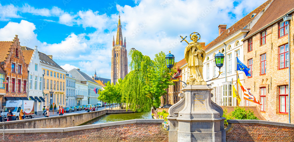 Obraz premium Scenic view of Bruges old town, statue of St John Nepomucene on Wollestraat bridge, Belgium