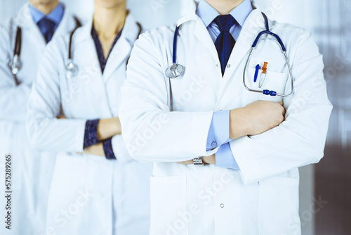 Group of modern doctors standing as a team with crossed arms and stethoscopes in hospital office. Physicians ready to examine and help patients. Medical help, insurance in health care