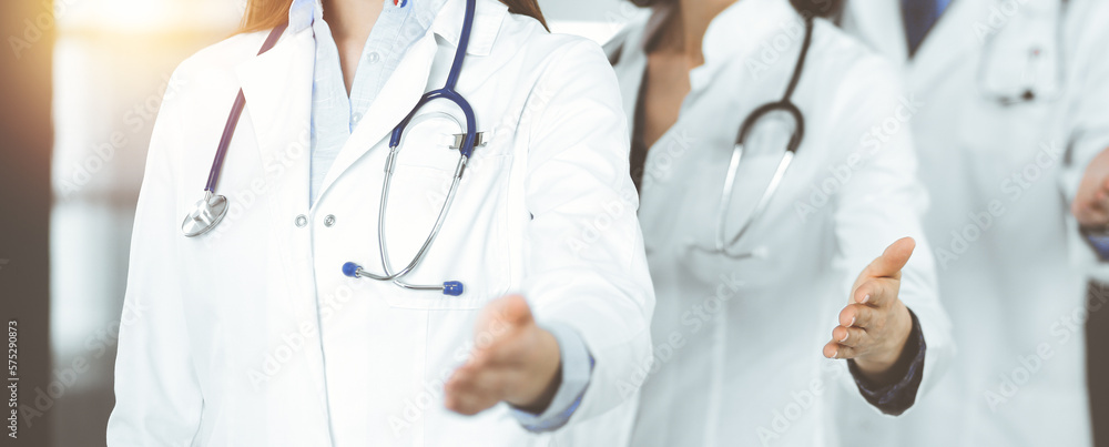 Group of doctors are standing as a team while offering their helping hands for shaking hand or saving people's life. Medicine concept during Coronavirus pandemic. Covid-2019 Group of doctors are standing as a team while offering their helping hands for shaking hand or saving people's life. Medicine concept during Coronavirus pandemic. Covid-2019