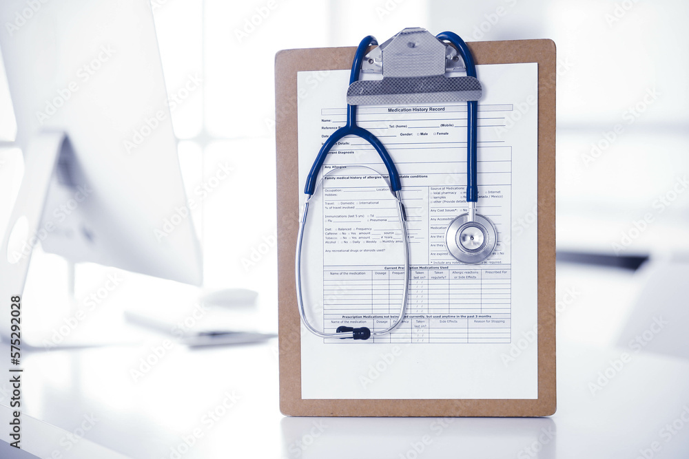 Stethoscope and clipboard with medication history records are on the table at the doctor's working place. Medicine and health care concept Stethoscope and clipboard with medication history records are on the table at the doctor's working place. Medicine and health care concept
