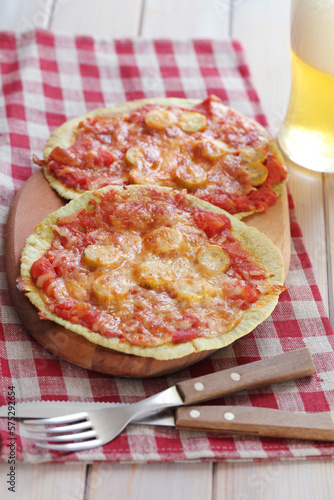 Sausage and tomatoes tortilla pizzas on a wooden board served with light beer