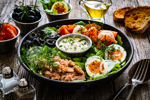 Nicoise salad - tuna  hard boiled eggs  greens  tomatoes and black olives 