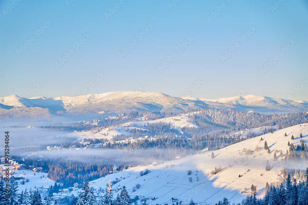 Picturesque landscape of winter hills covered with pine forests. Misty mountains in winter. Foggy winter landscape. Scenic view. Sunrise.