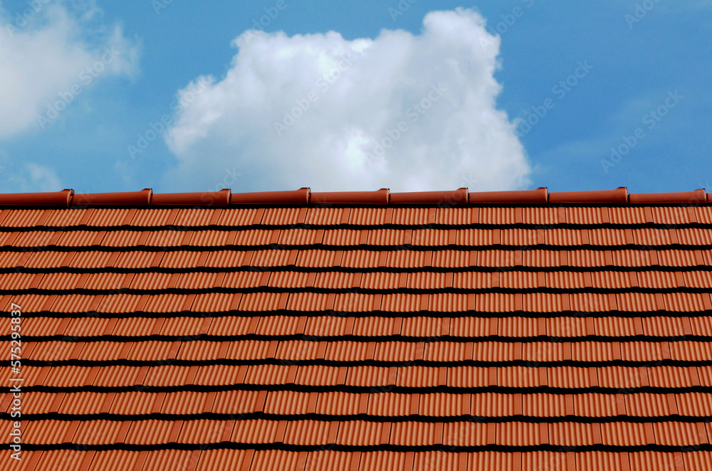 sloped red clay roof ridge detail. new bright clay house roof tiles. construction industry and building materials concept. clear blue sky. bright sunlight sloped red clay roof ridge detail. new bright clay house roof tiles. construction industry and building materials concept. clear blue sky. bright sunlight