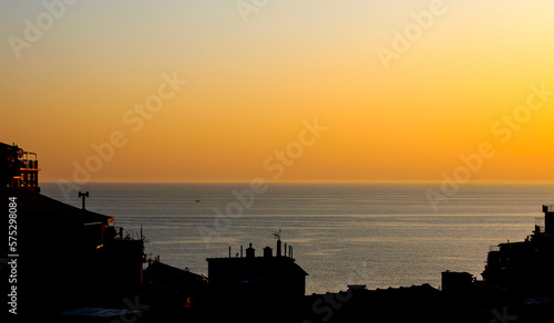 View on sea through buildings silhouettes sunset.