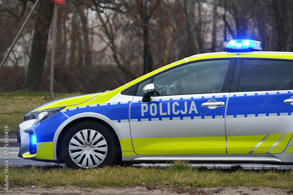 Radiowóz polskiej policji drogowej z policjantem, nowy  podczas służby w mieście. Nowe barwy.  - obrazy, fototapety, plakaty 