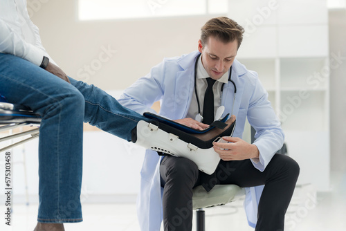 The doctor puts a splint on a patient with a leg. photo