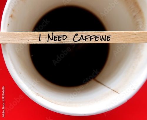 Fototapeta Wood coffee stirrer with handwritten text I NEED CAFFEINE on paper cup, concept