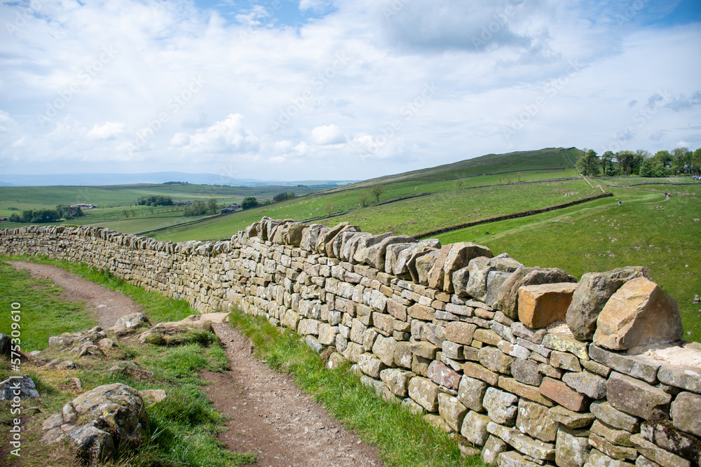 A section of Hadrian's Wall close to Milecastle 39 (Roman military base) and adjacent to a footpath route. in Northumberland National Park. With blue cloudy skies during summer 2022