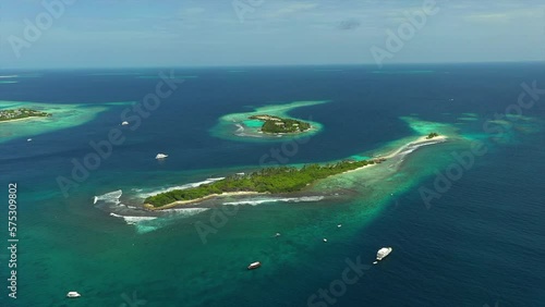 Aerial Panning Scenic View Of Green Island Surrounded By Boats, Drone Flying Over Wavy Sea - Thulusdhoo, Maldives photo