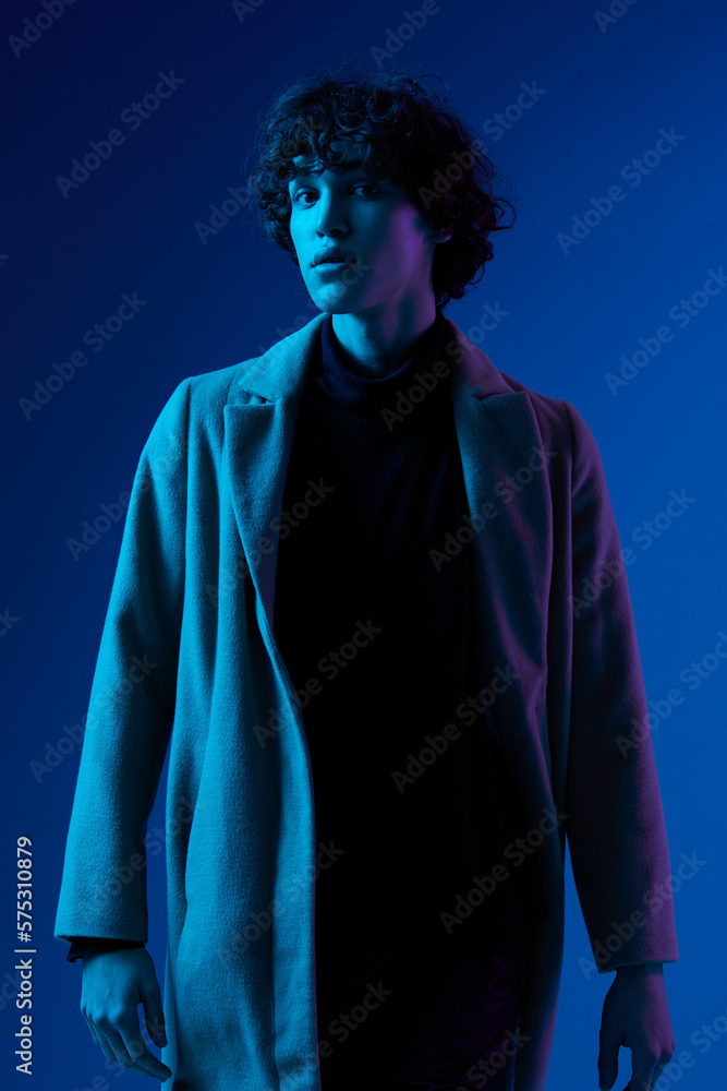 Man in fashion coat on dark blue background, neon light, style and trends, mixed light, men's fashion Man in fashion coat on dark blue background, neon light, style and trends, mixed light, men's fashion