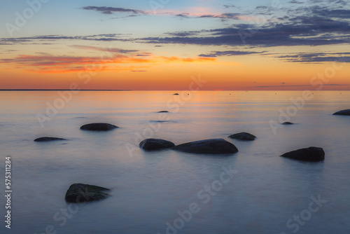 Red colored sky over a rocky seashore. Sunset landscape.