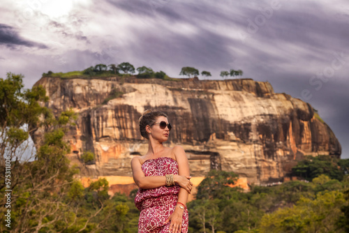 Portrait woman in sunglasses posing in front Sigiriya rock fortress at Sri Lankan sight landmark nature background. Cute lady traveler enjoying at tropical journey, Sri Lanka. Copy ad text space photo