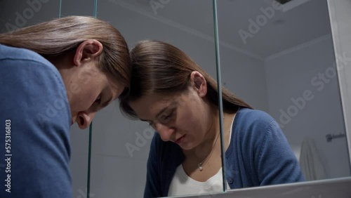 Portrait of angry and stressed woman leaning on mirror and looking in reflection. Concept of depression, suicide, stress, mental illness, loneliness and frustration