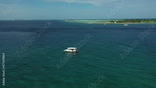 Aerial Forward Shot Of White Yacht Moving In Sea By Island On Sunny Day - Thulusdhoo, Maldives photo